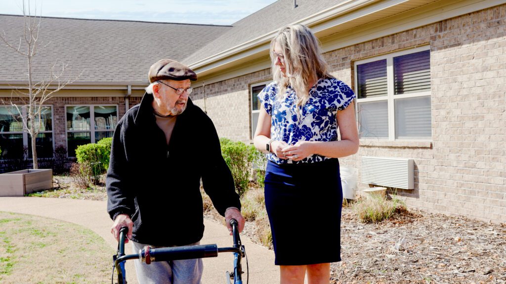 A man and staff worker walk around a trail available to short term care patients