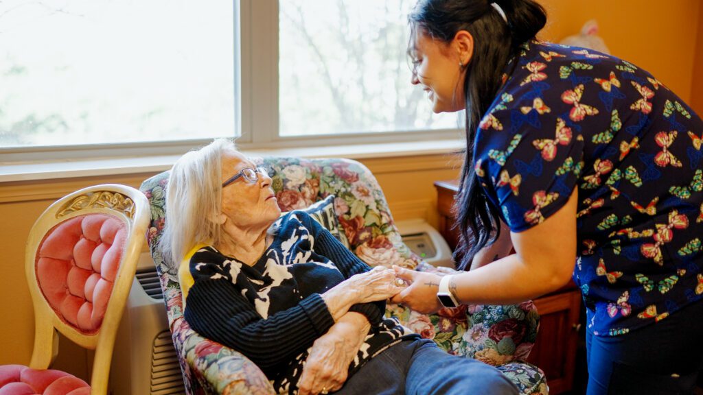 A nurse holds hands with a resident at a skilled nursing facility